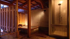 A sauna room with wooden beams, a bench, and a glass-enclosed shower area. - Kusatsu Onsen Boun (Kusatsu)
