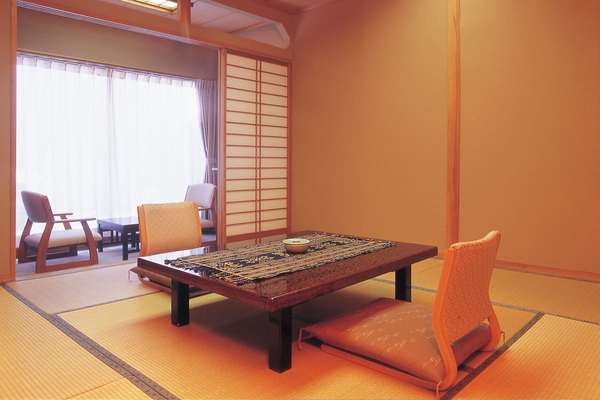 Una habitació japonesa tradicional amb tatami, una taula baixa amb un bol i dues cadires.