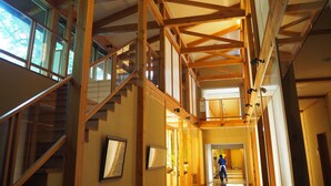 A spacious interior with wooden beams, a glass staircase, and a hallway leading to another room. - Kusatsu Onsen Boun (Kusatsu)