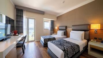 Habitación de hotel con dos camas, un escritorio, un televisor y un balcón con vistas.
