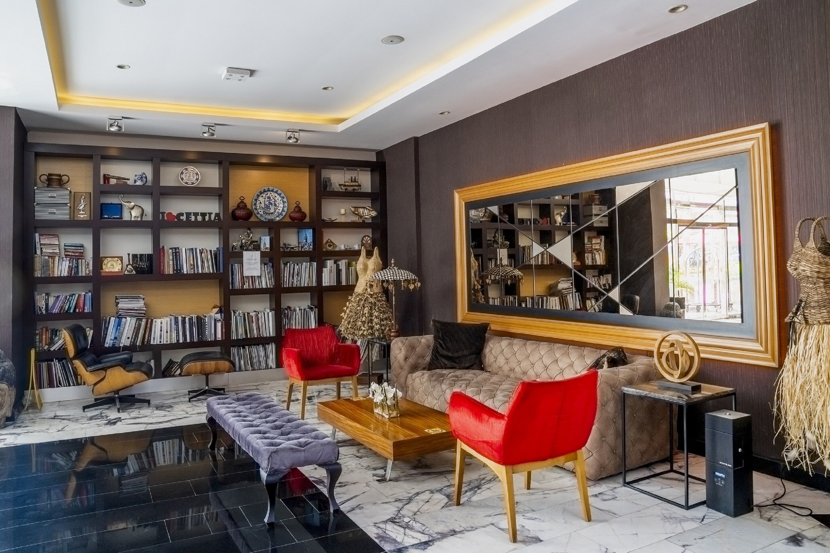 Un salon moderne avec une grande bibliothèque, un canapé, une table basse et un grand miroir.