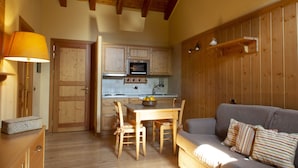A cozy kitchen with wooden cabinets, a dining table with chairs, a sofa, and a lamp.