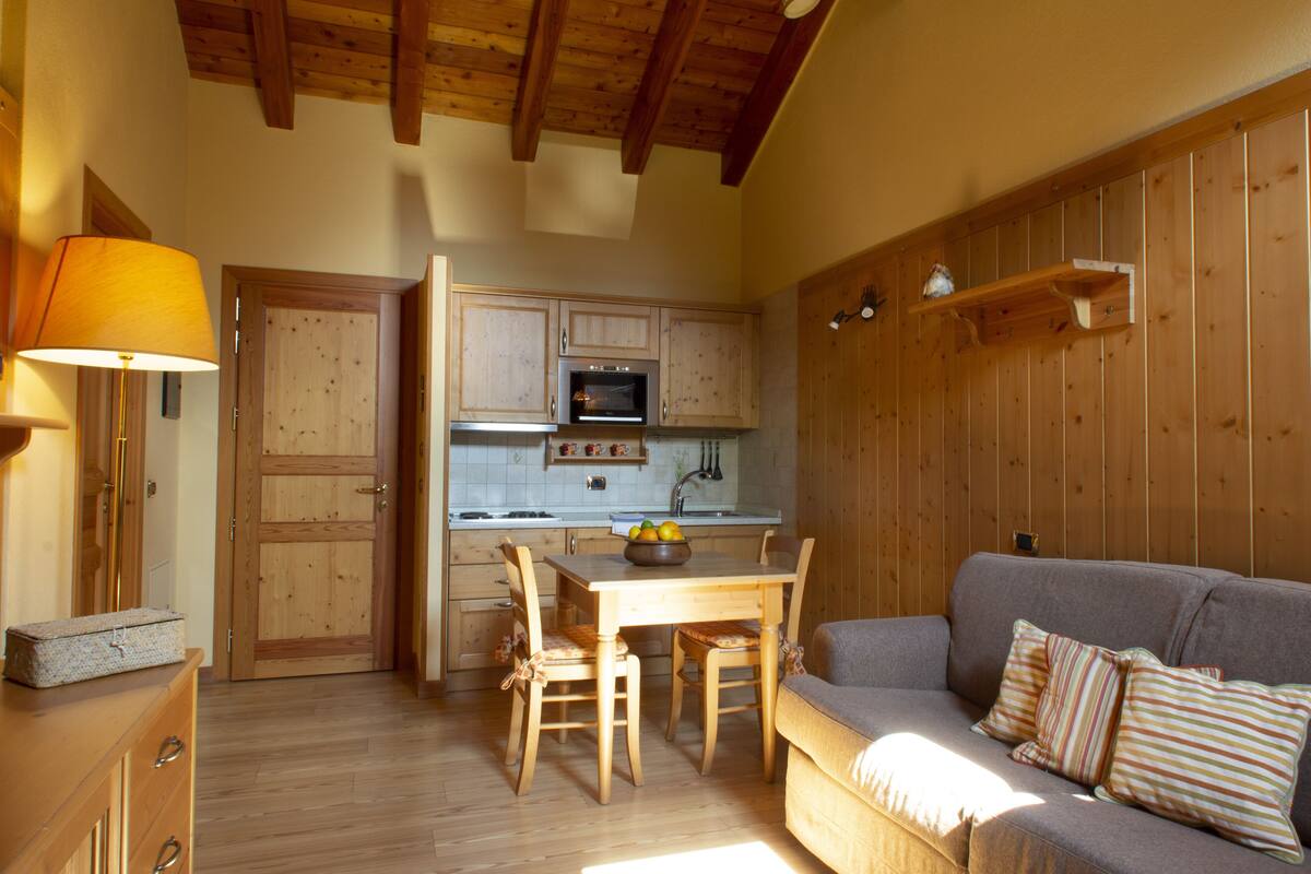Una cocina acogedora con armarios de madera, una mesa de comedor con sillas, un sofá y una lámpara.