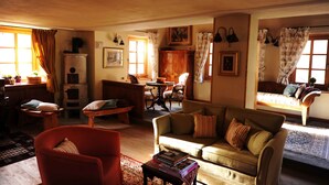 A cozy living room with a sofa, armchair, and a dining table.