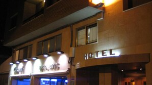 Hotel amb un senyal distintiu, entrada ben il·luminada i façana visible amb il·luminació.