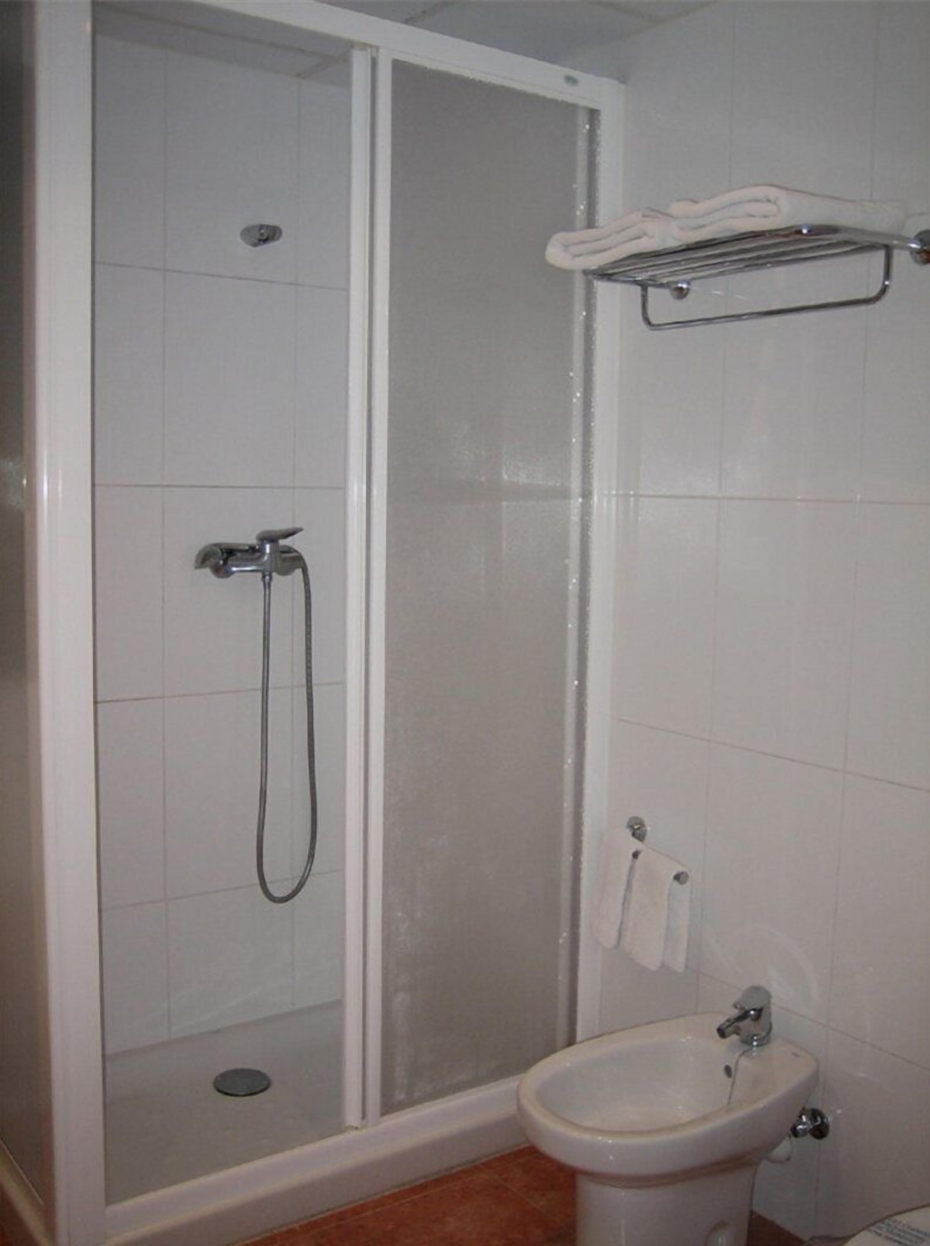Un baño con cabina de ducha, lavabo y barra para toallas.