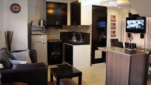 Een knus woongedeelte met kitchenette, eethoek en zithoek met een bank en salontafel.