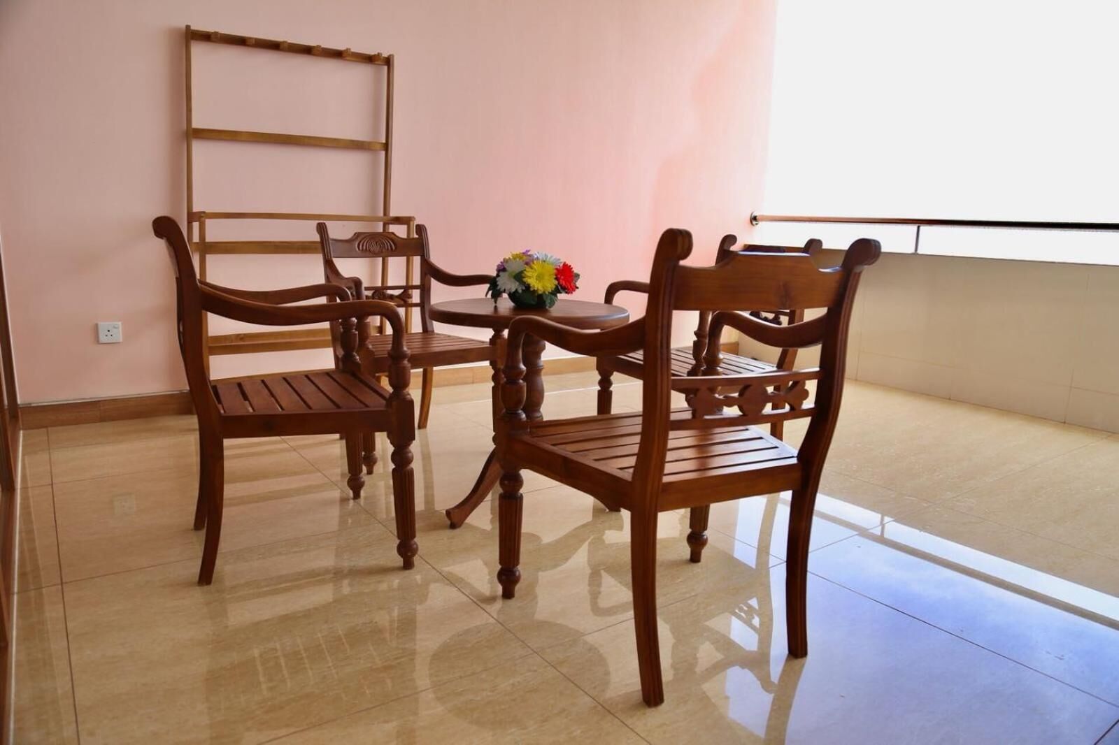 A room with a wooden dining table and four chairs, a vase with flowers, and a ladder against the wall.