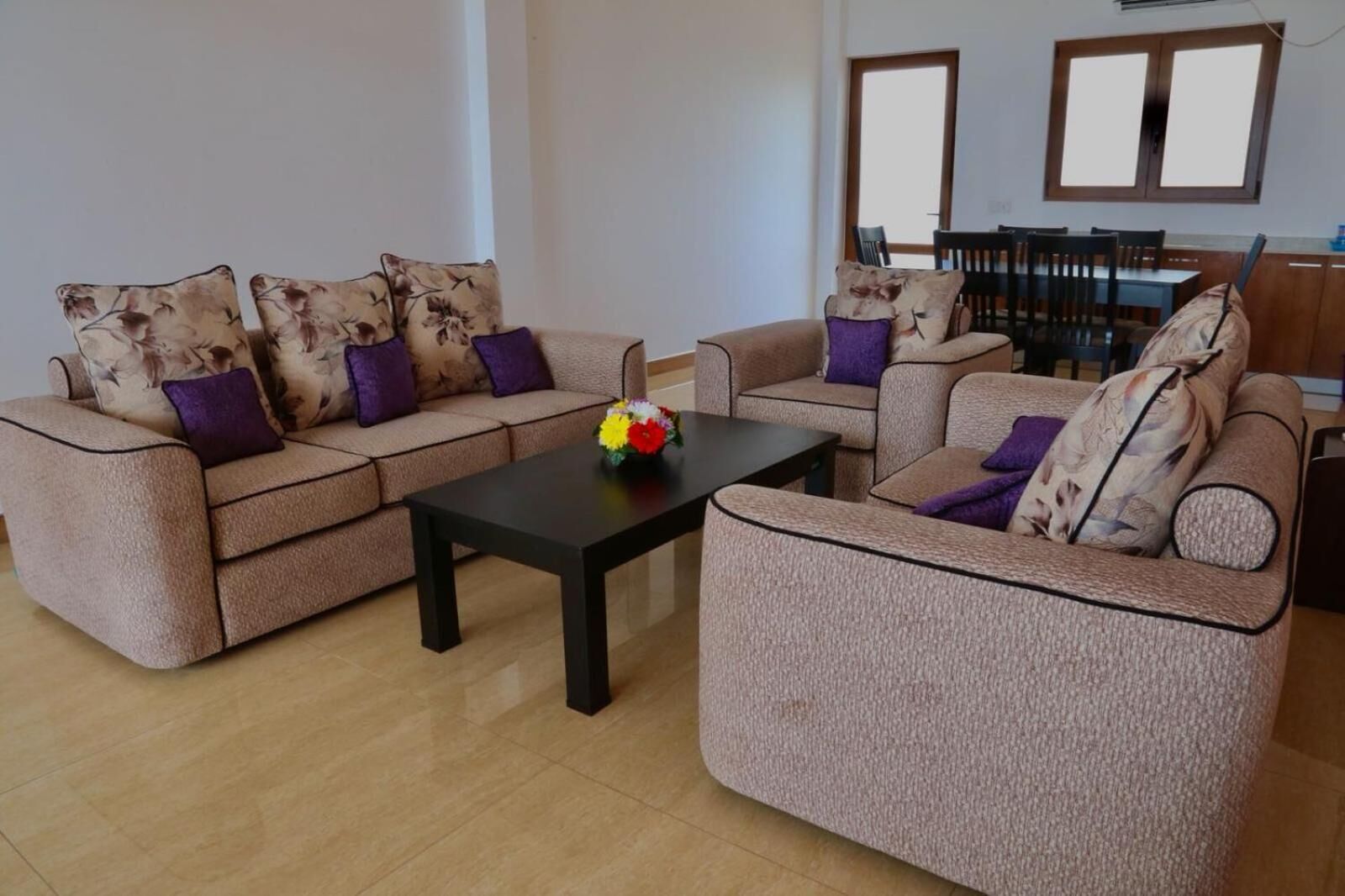 A living room with two sofas, a coffee table, and a dining area with chairs and a table.