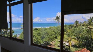 A room with large windows overlooking a tropical beach and dense greenery. - Paradise Beach Resort (Thalaramba)