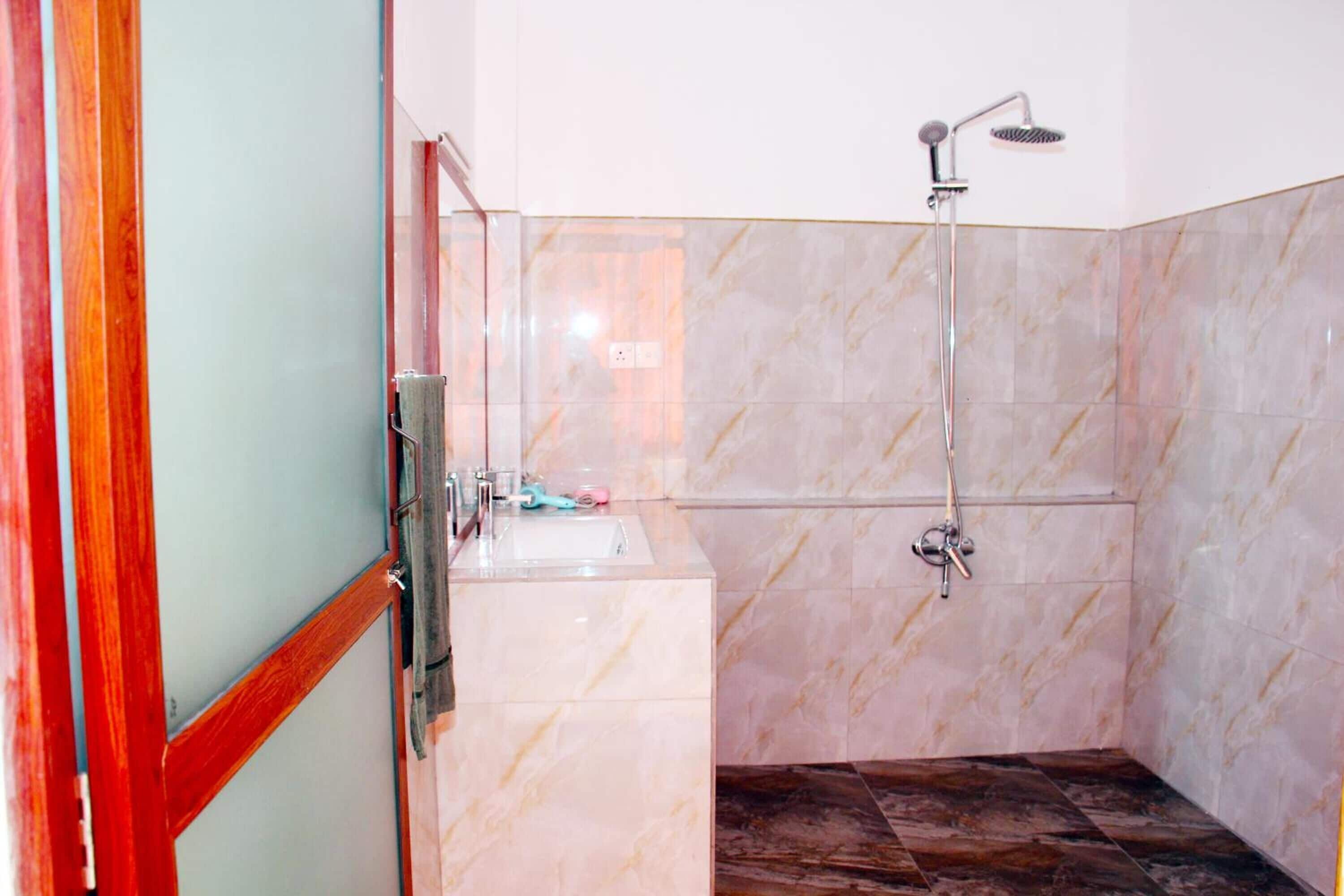 Een badkamer met een douche, wastafel en spiegel.