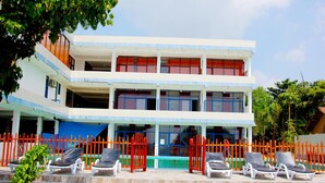 A two-story building with a swimming pool, outdoor seating, and a red fence. - Paradise Beach Resort (Thalaramba)