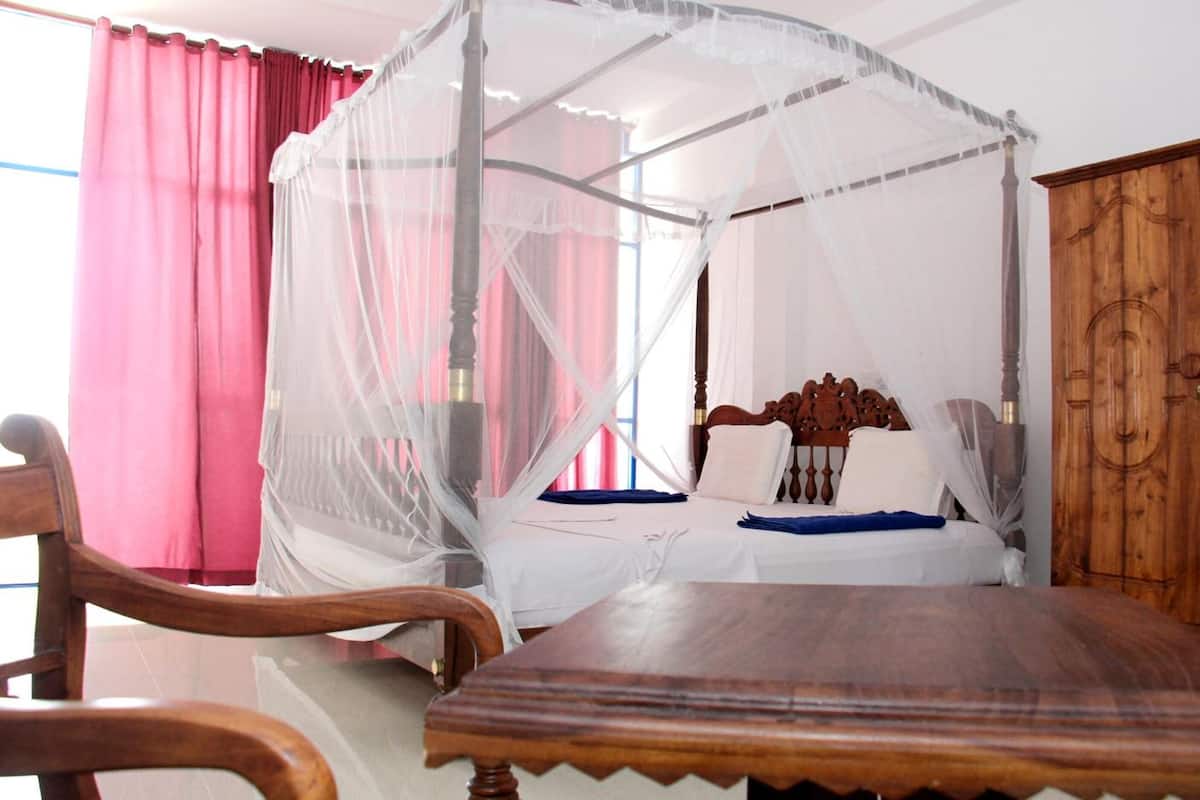 Quarto com cama, mesa e guarda-roupa de madeira.
