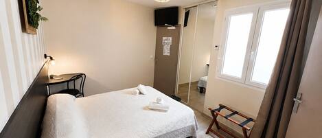 Habitación de hotel con cama, mesita de noche, lámpara y ventana con cortinas.
