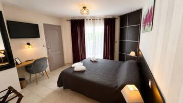 Een hotelkamer met een bed, bureau, stoel en een aan de muur bevestigde televisie.