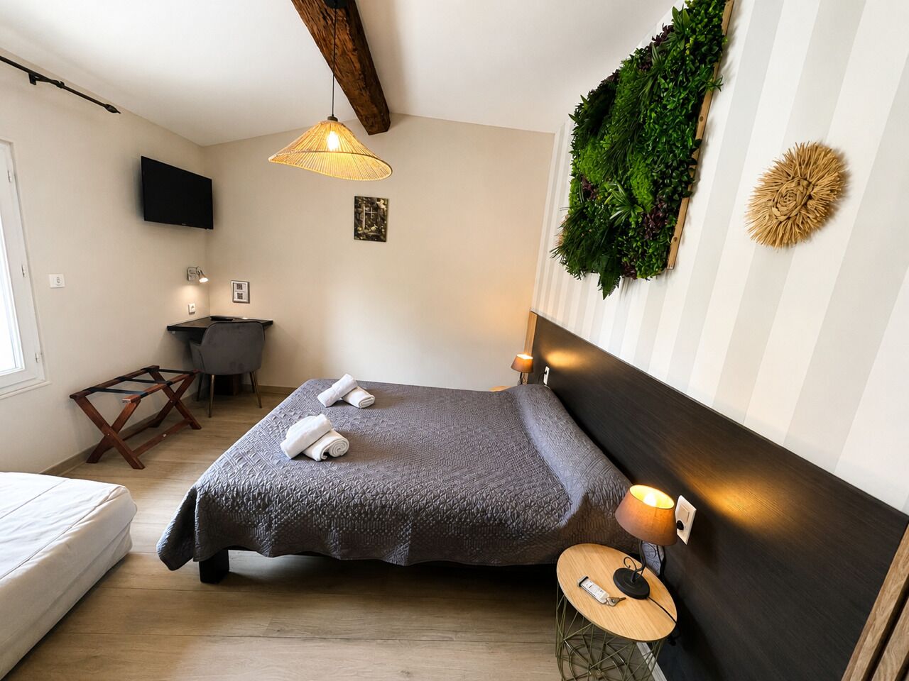 Un dormitorio con cama, mesita de noche, lámpara y televisor montado en la pared.