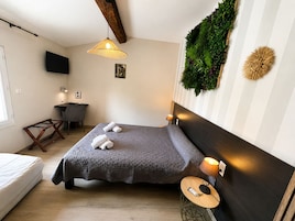 Un dormitorio con cama, mesita de noche, lámpara y televisor montado en la pared.