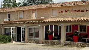 Un edificio de dos pisos con techo de tejas y un letrero que dice "Le St Germain".