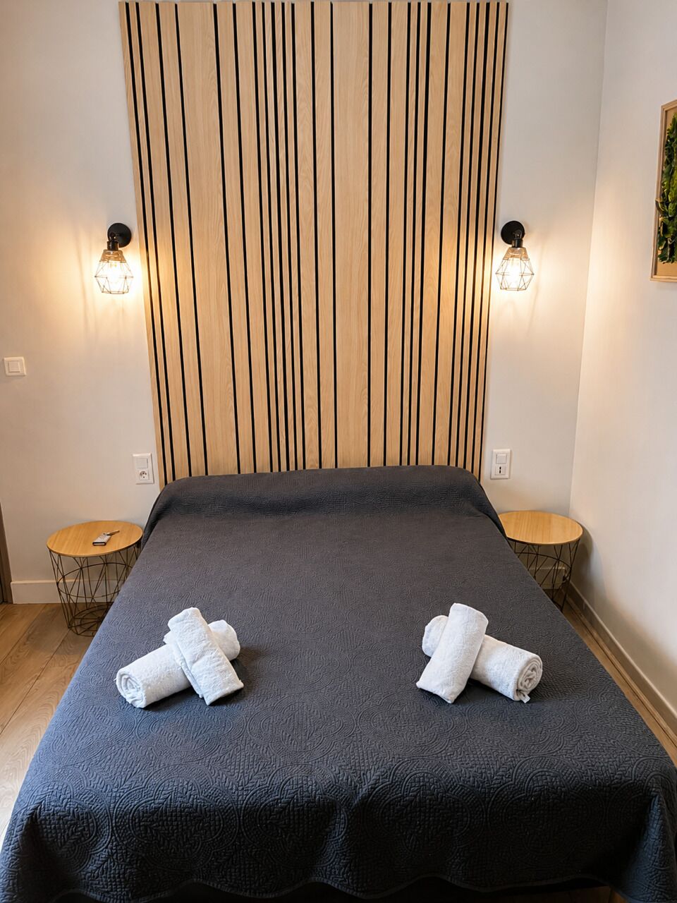 Une chambre d’hôtel avec un lit, deux tables de chevet et un mur recouvert de lattes de bois.