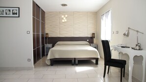 Un dormitorio con cama, mesitas de noche, un escritorio con silla y un armario.