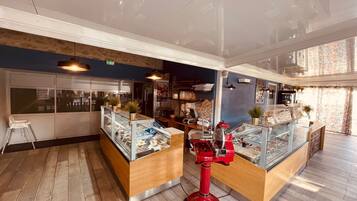 L'intérieur d'un café moderne, avec un plancher en bois, des vitrines et une machine à expresso rouge.