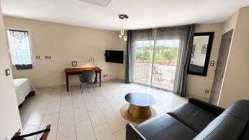 Una sala de estar moderna con un sofá, una mesa de comedor con sillas, un televisor y un ventanal con vistas.