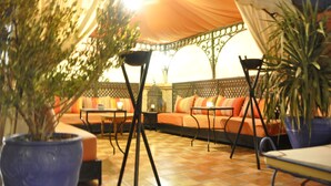 Un espace extérieur accueillant, aménagé avec une tente, des canapés confortables et des plantes en pot.