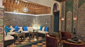 Une pièce avec un mur orné de motifs, un canapé avec des coussins bleus, une table basse et un fauteuil.