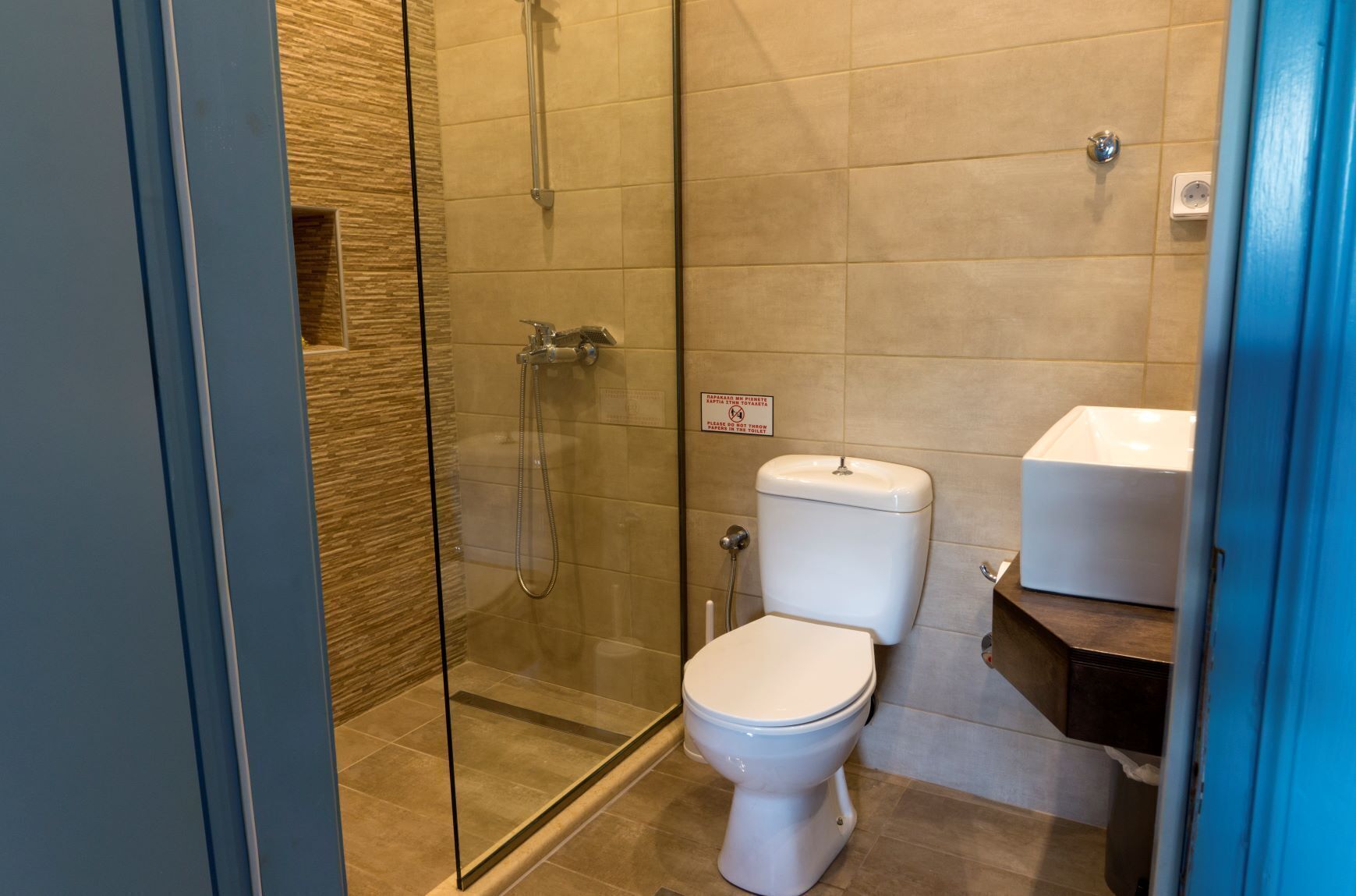 A bathroom with a glass-enclosed shower, a toilet, and a sink.
