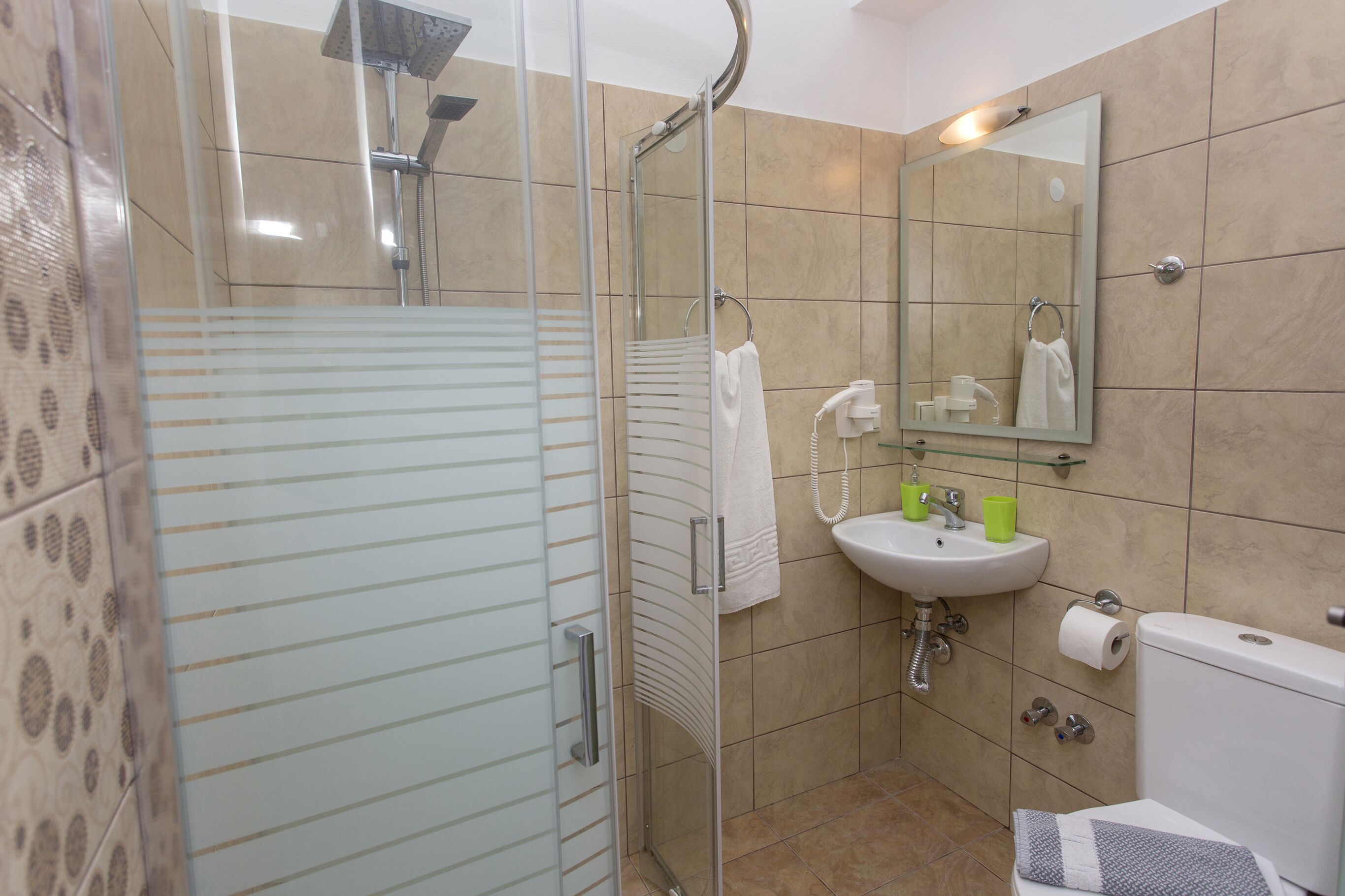 A bathroom with a glass shower enclosure, a sink with a mirror, and a toilet.