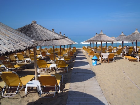On the beach, sun loungers, beach umbrellas, beach towels. Hotel Loukas Vrachos