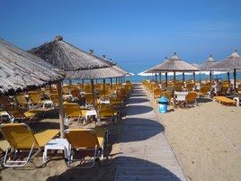 En la playa, sillas reclinables de playa, sombrillas, toallas de playa