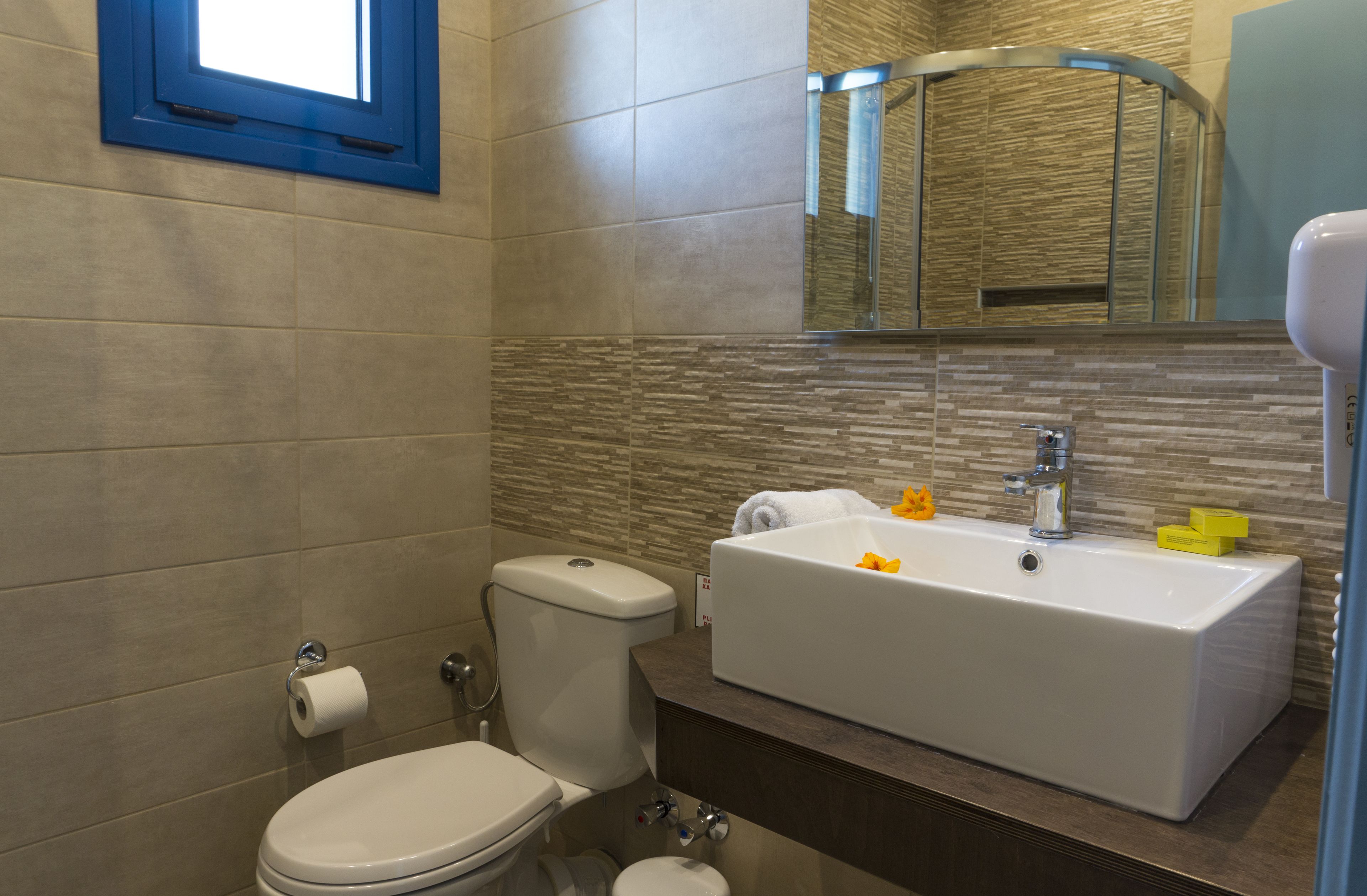 Een moderne badkamer met toilet, wastafel en spiegel.