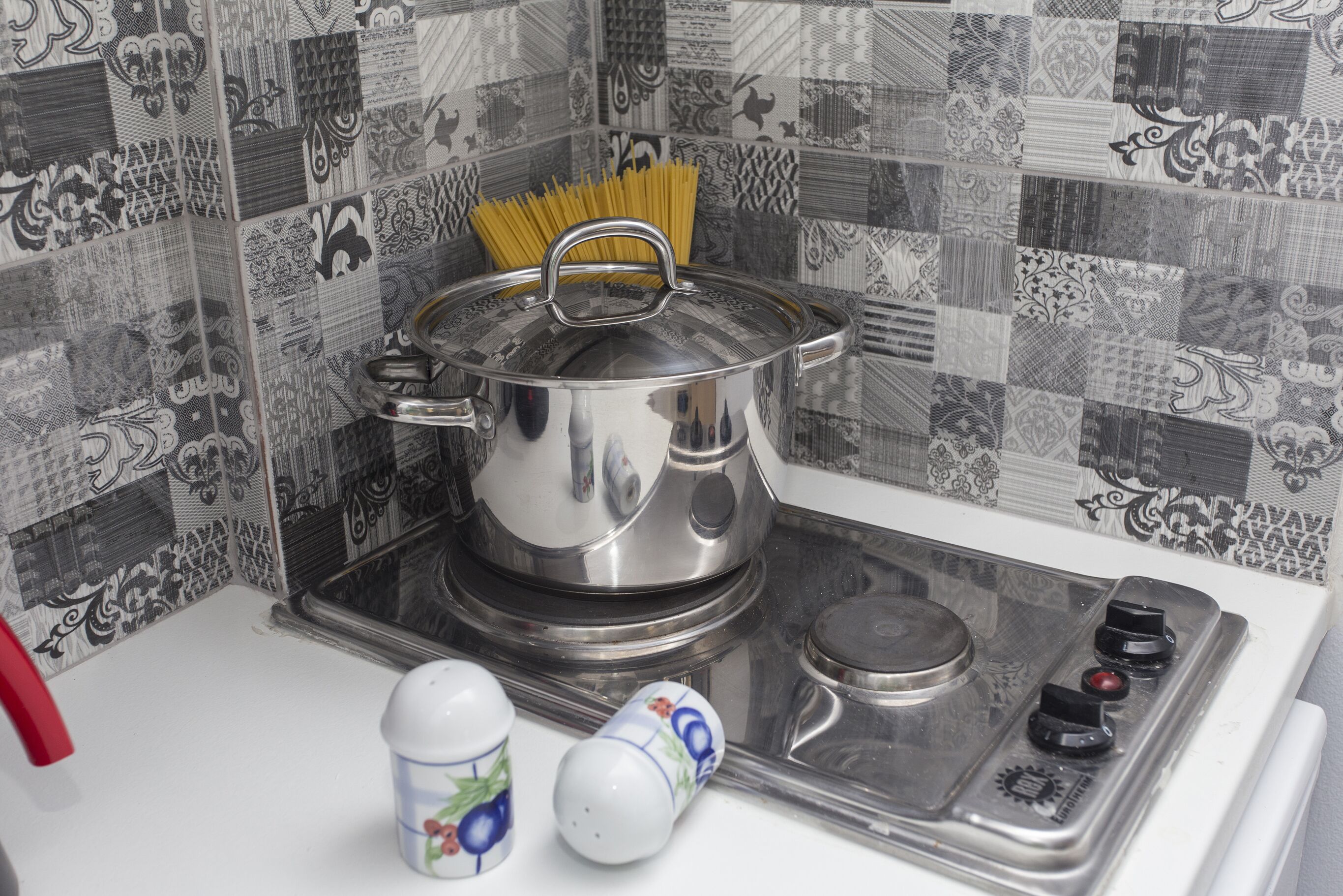 A kitchen with a stove, a pot, and a set of salt and pepper shakers.