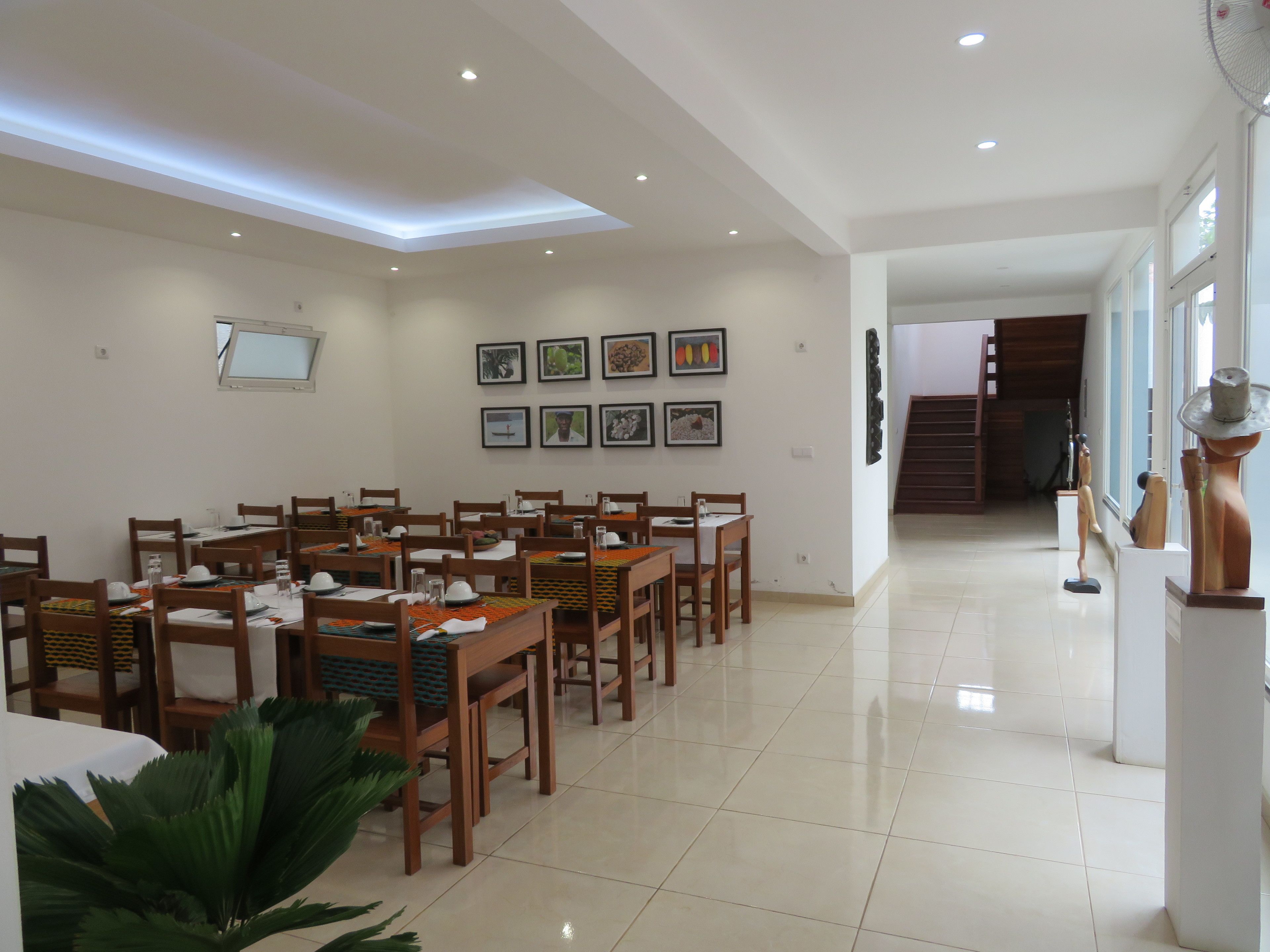 A spacious dining area with wooden tables and chairs, a skylight, and framed artwork on the walls.