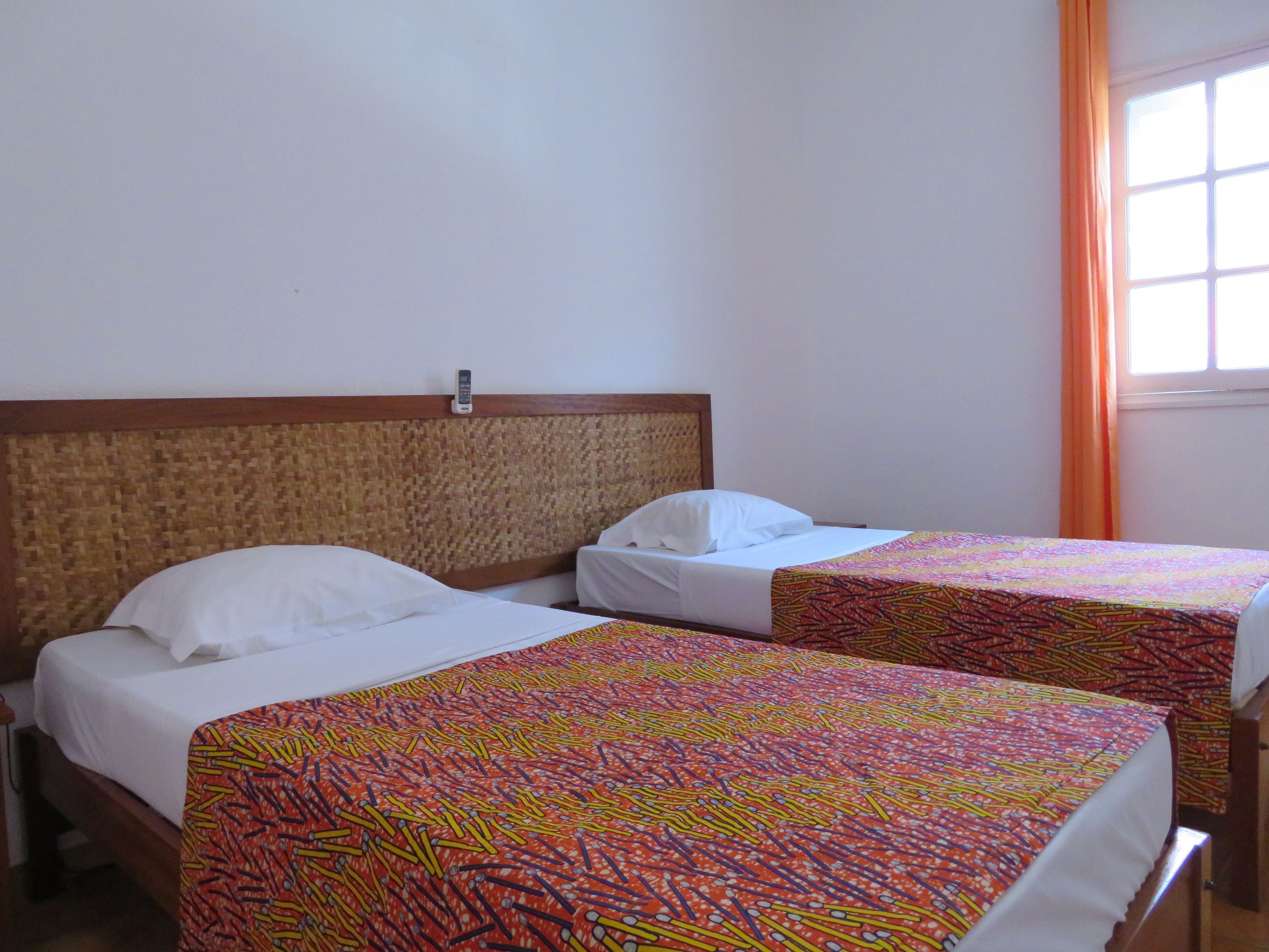 Two single beds with wooden headboards, white bedding, and colorful bedspreads.