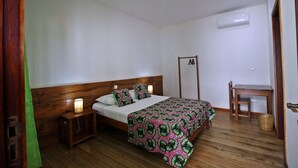 Un dormitorio con cama de madera, lámparas de noche, un escritorio y una silla.