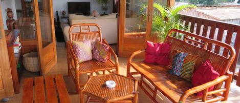 A wooden outdoor seating area with a sofa, chairs, and a table.