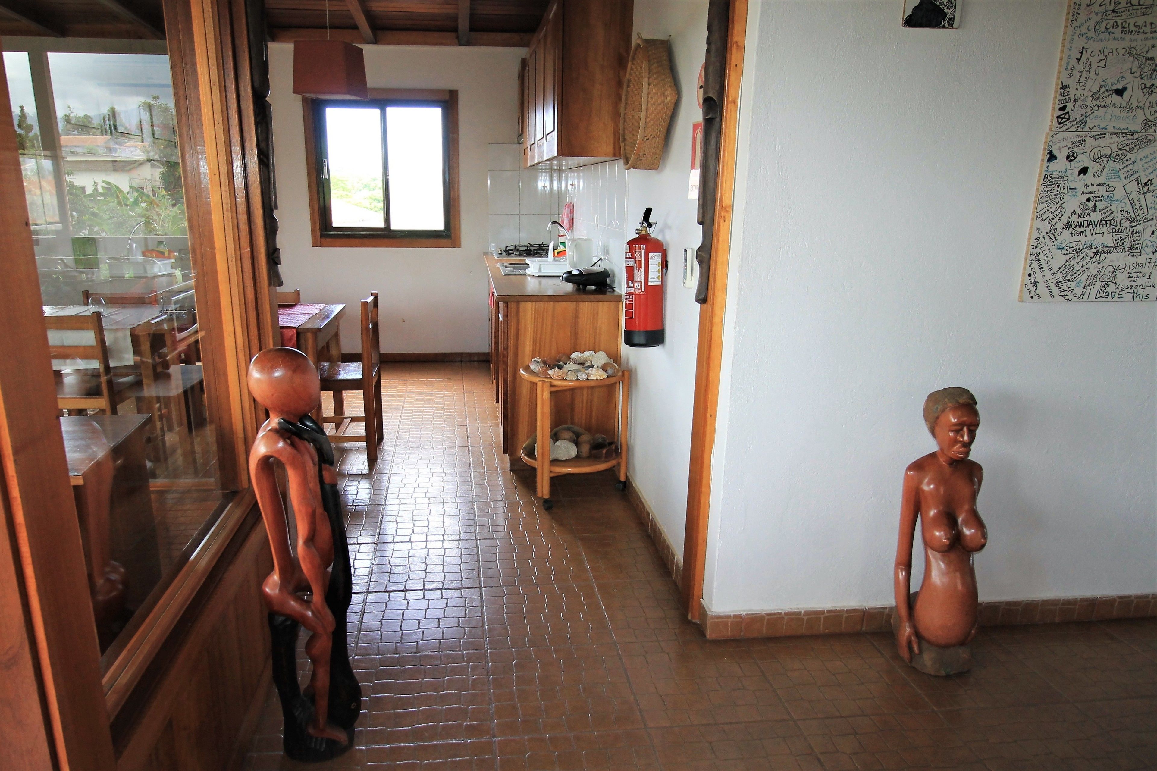 Una cocina con armarios de madera, piso de baldosas, una ventana y un extintor.
