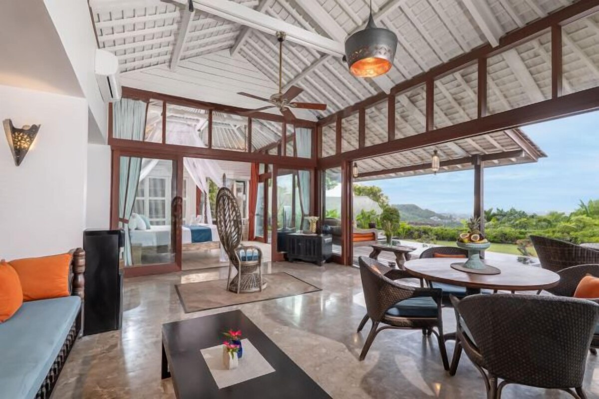 Un espacio interior amplio con techo alto, ventanas grandes y vistas al exterior.
