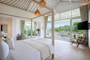 A spacious bedroom with a large bed, a balcony with seating, and a TV mounted on the wall.