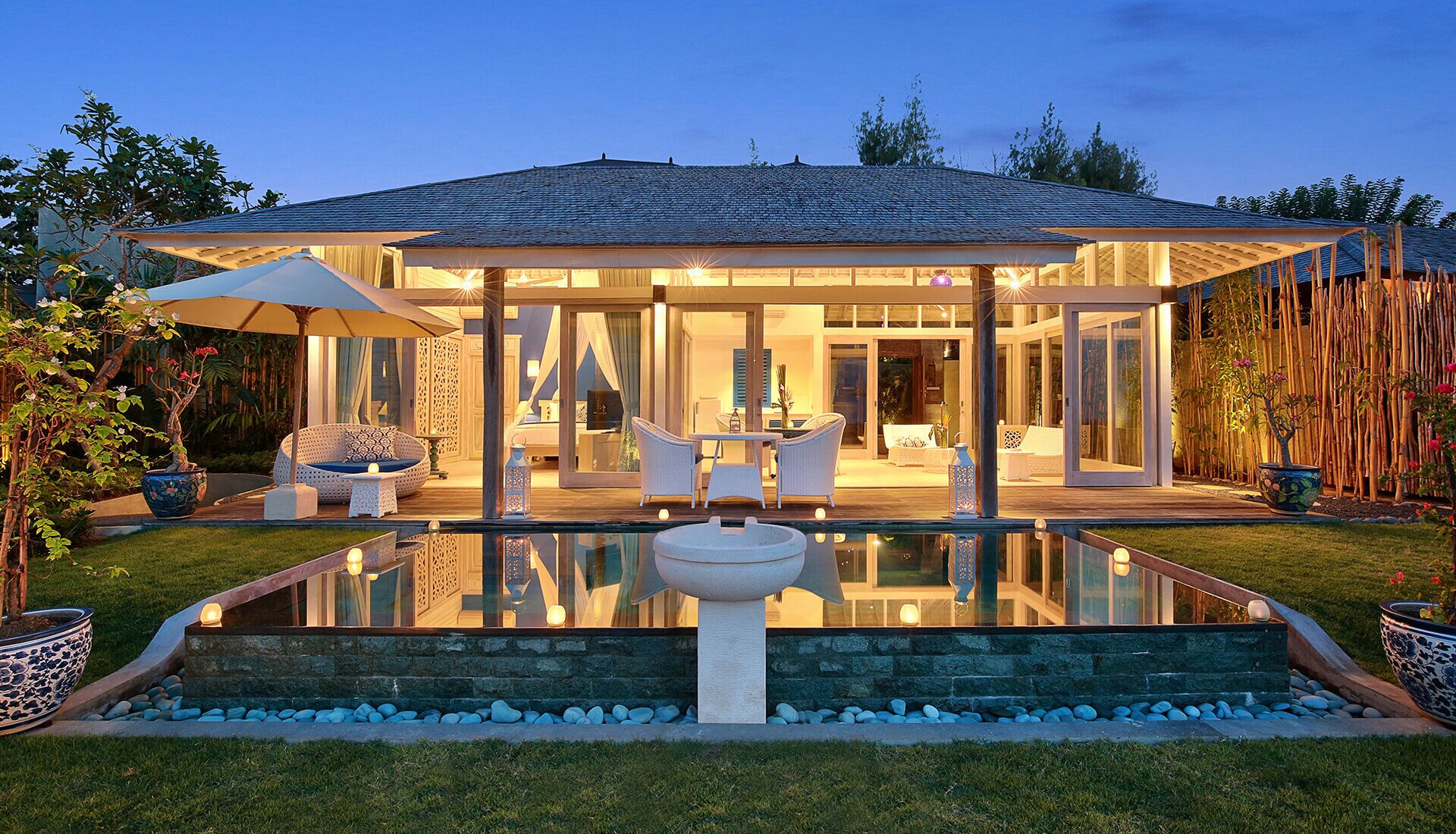 A modern house with a glass-enclosed patio, a swimming pool, and a well-maintained garden.