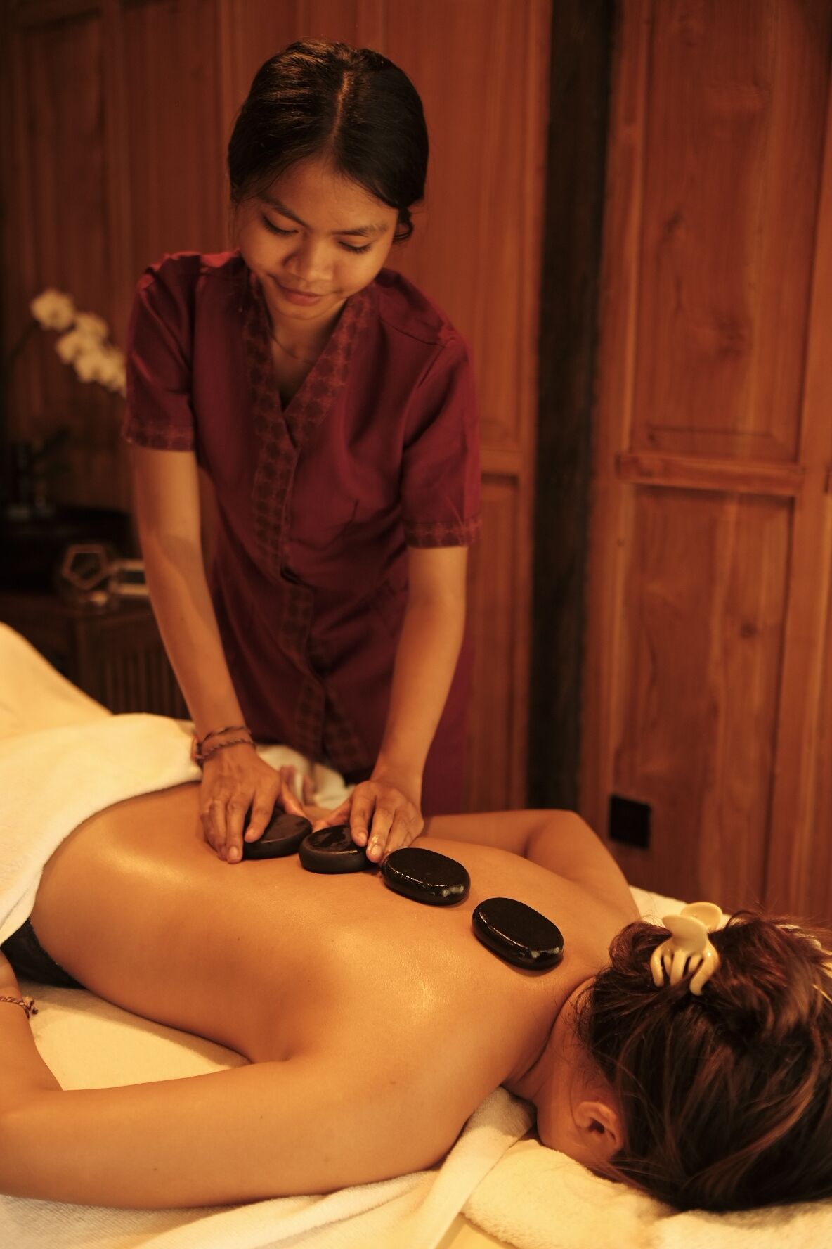 A person receiving a back massage with heated stones.