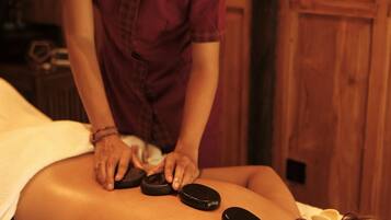 A person receiving a back massage with heated stones.