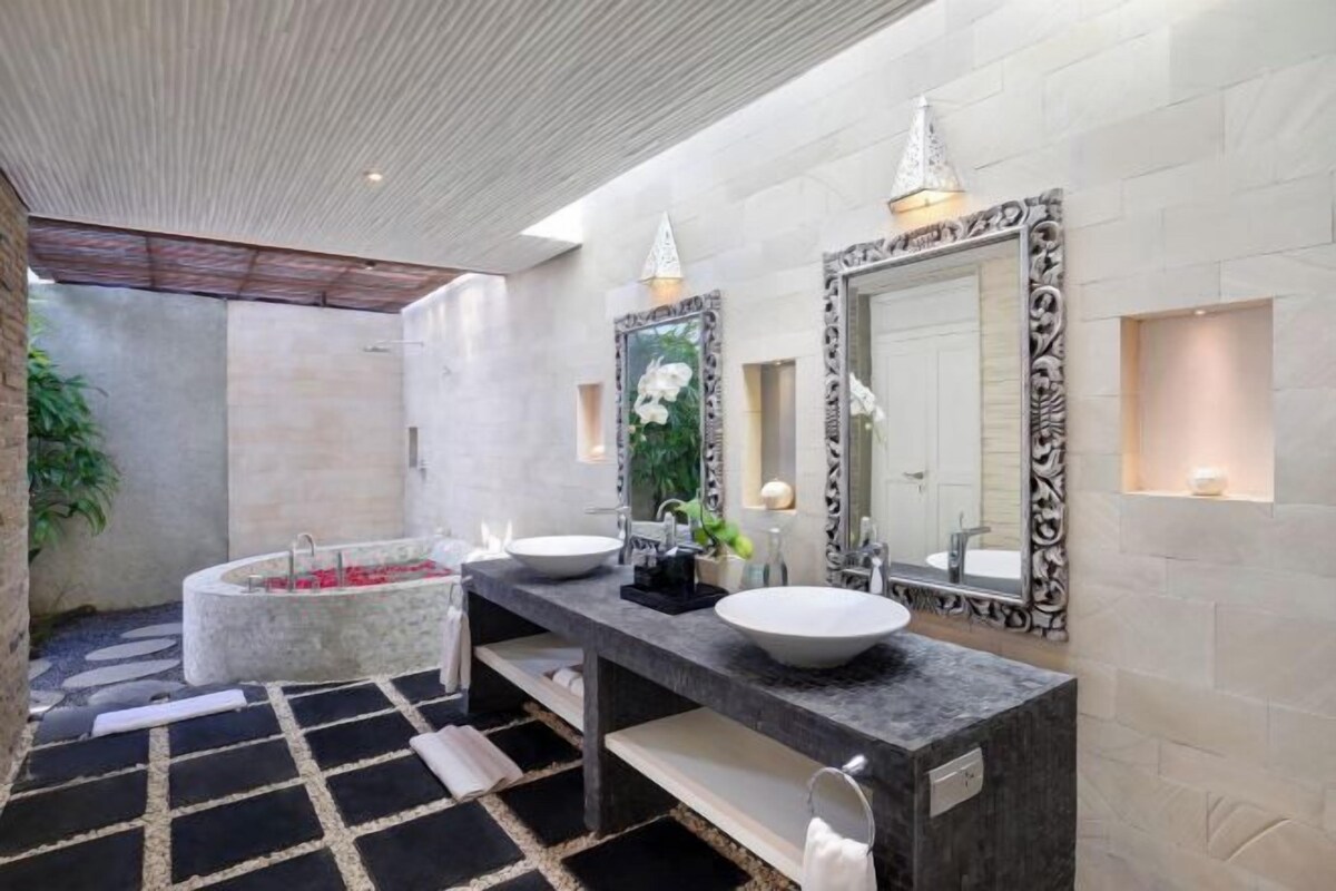 Un baño moderno con una bañera grande, dos lavamanos y un espejo amplio.