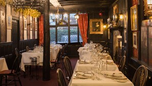 A restaurant with multiple tables set for dining, featuring chandeliers and framed artwork on the walls. - The Mermaid Inn (Rye)