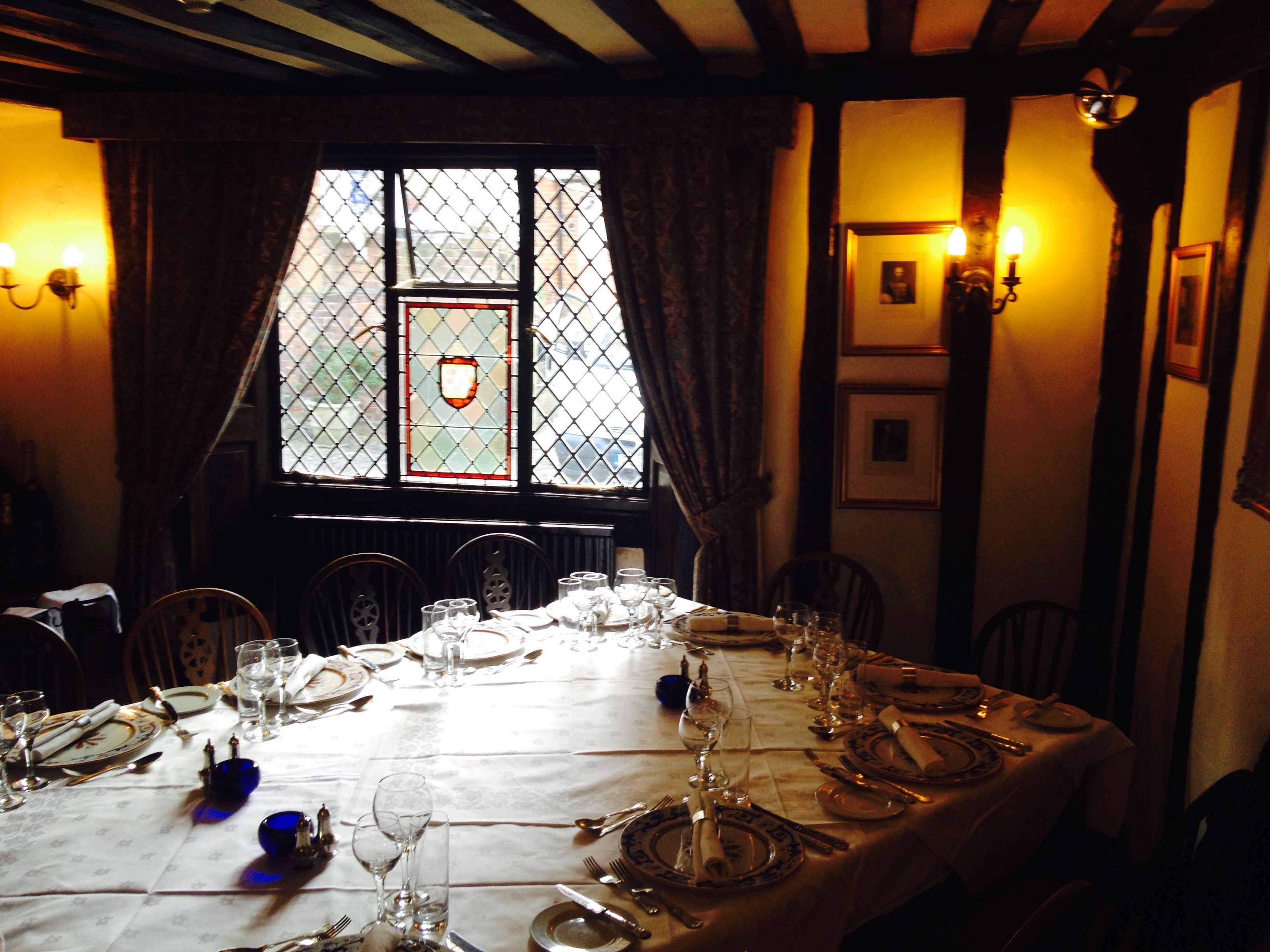 A dining table set for a meal with chairs around it, a window with a view, and wall-mounted lights.