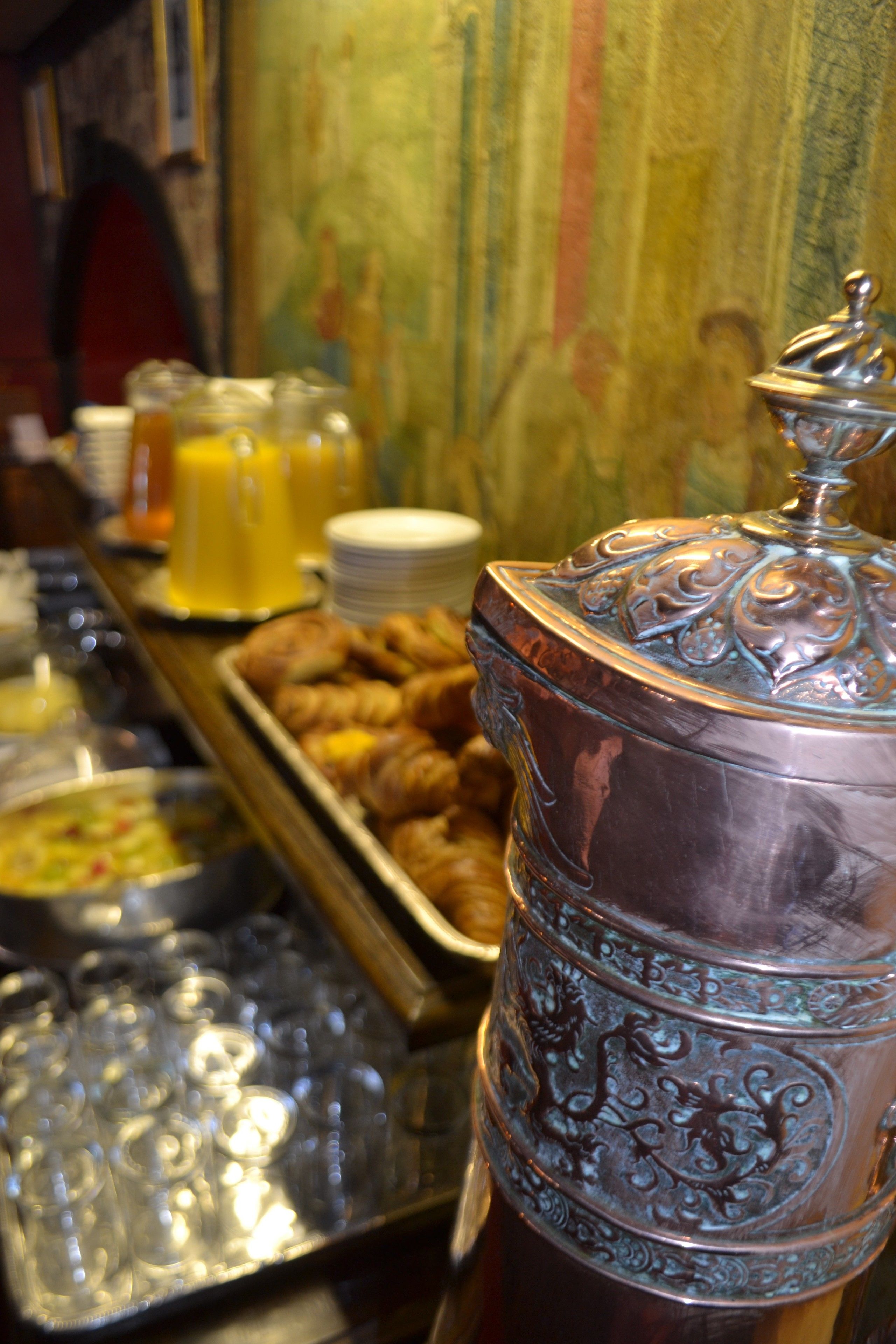 A buffet with various food items and a decorative metal container.