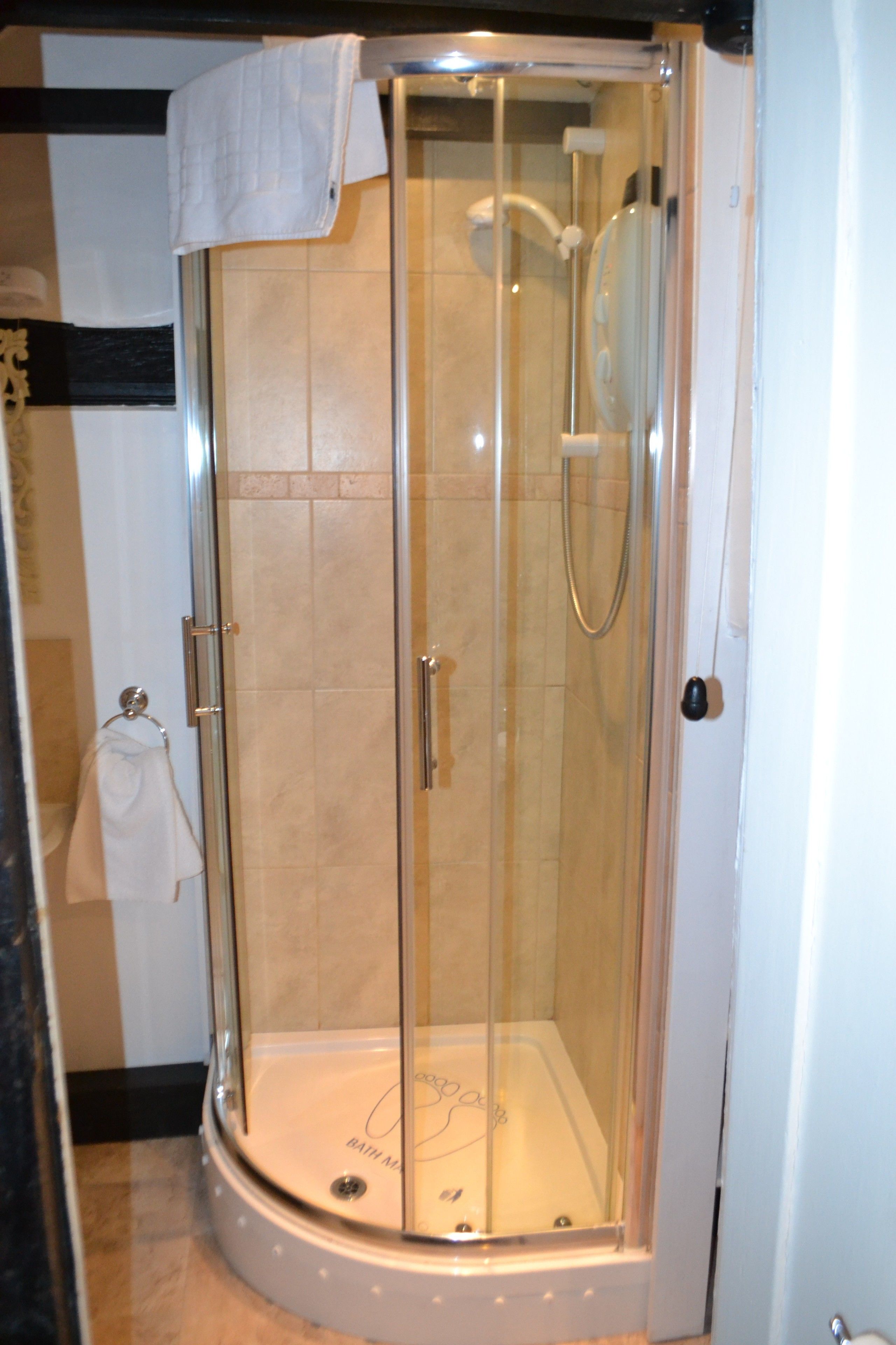 A glass-enclosed shower stall with a white towel hanging on the door.