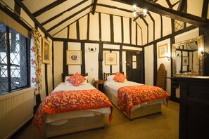 A room with two beds, a large mirror, and a window with curtains.